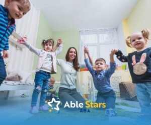 Children holding hands in a group activity with ABA therapist in a classroom setting.