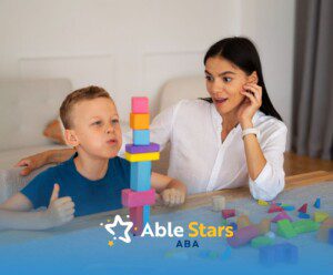 ABA therapist and autistic boy building a tall tower with colorful wooden blocks.