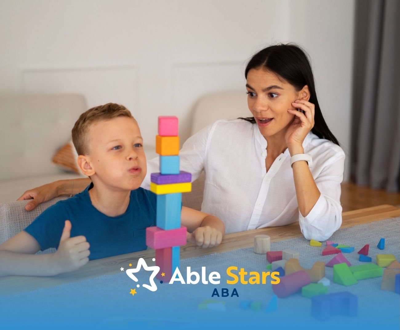 ABA therapist and autistic boy building a tall tower with colorful wooden blocks.