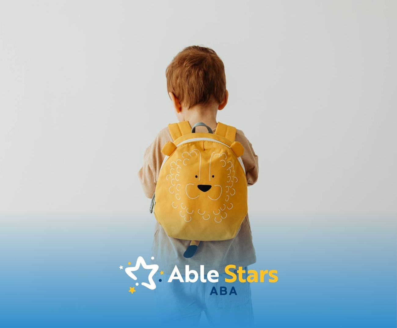 An autistic toddler with a yellow lion backpack standing against a plain white background in Maryland.