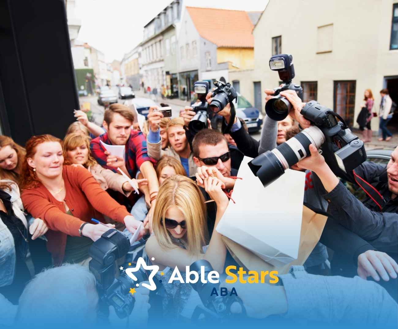 A crowd of enthusiastic photographers and fans surrounds a person with long blonde hair. Cameras flash, capturing the moment in a bustling urban street. Emotions of excitement and urgency fill the scene.