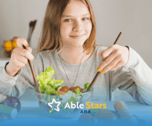 A girl with autism holding a wooden spoon and fork while eating a bowl of salad