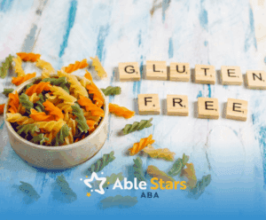 A bowl of uncooked pasta beside scrabble letters that spells the words "gluten free"