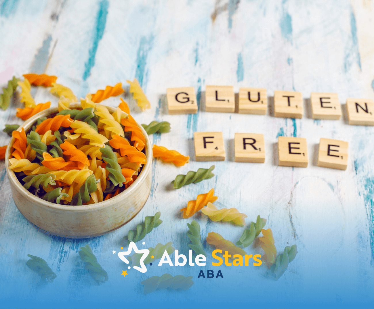 A bowl of uncooked pasta beside scrabble letters that spells the words "gluten free"