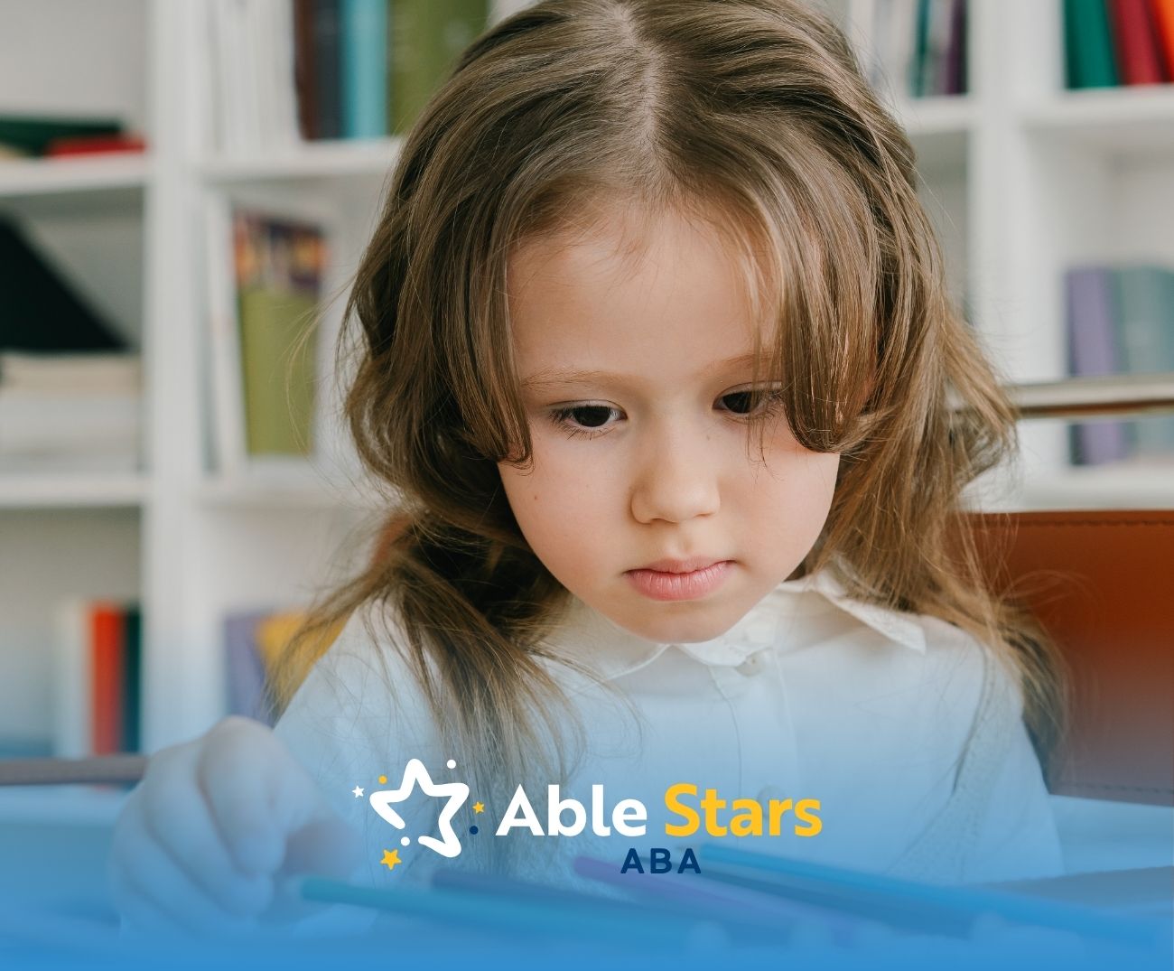 A little girl looking at crayons in front of her.