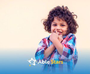 A little kid with wavy hair and using checkered shirt, smiling to the camera.
