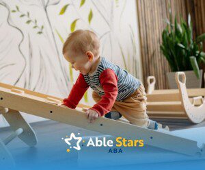 Autistic toddler climbing a wooden ramp in a playroom with nature-themed wall decor in Maryland.