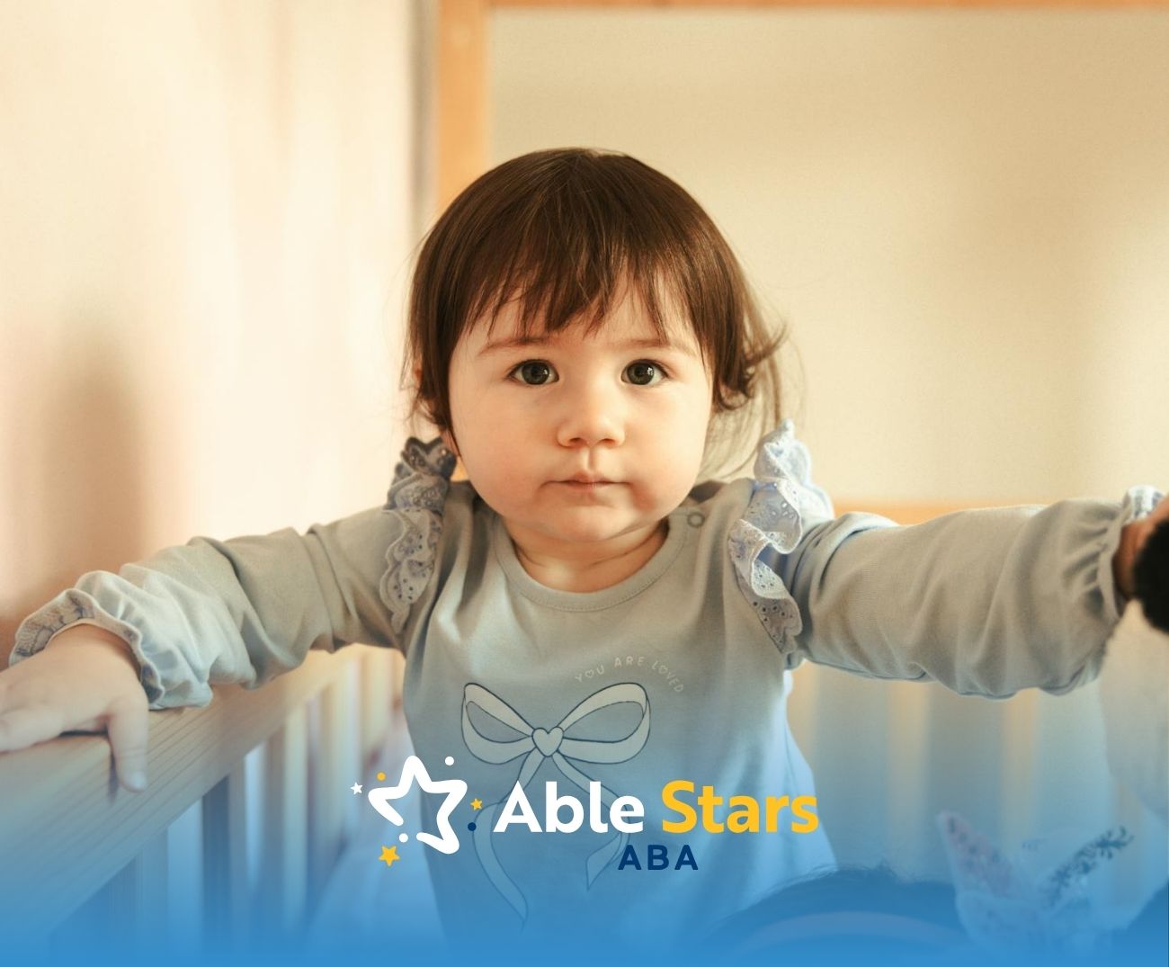 An autistic toddler girl holding onto crib rail and looking forward with a calm expression in MD.