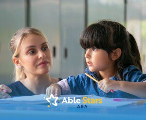 BCBA helping a young girl with a task at a desk.