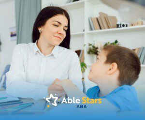 BCBA holding hands with a boy at a desk with colored pencils.