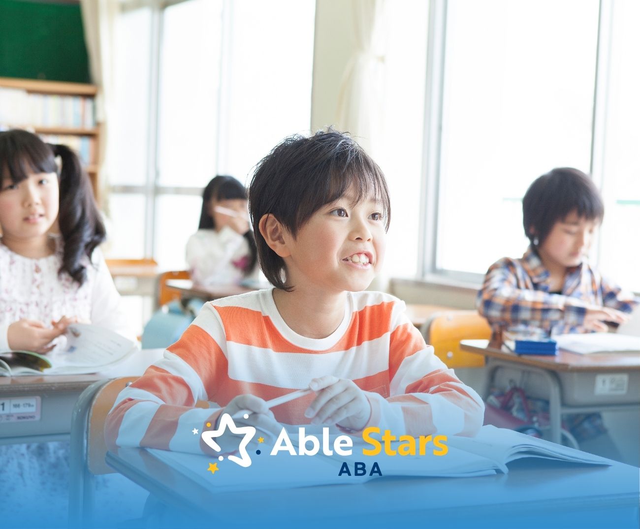 Smiling child in a striped shirt sits at a classroom desk, engaged and attentive. Other children study nearby. Bright, cheerful atmosphere.