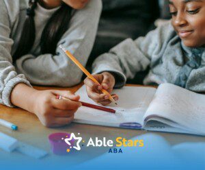 Two autistic children working together on schoolwork at a desk during an ABA therapy session in Maryland.