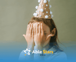 Young autistic girl covering her face with hands, wearing a party hat, avoiding eye contact in Maryland.