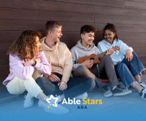 Group of teenagers sitting outdoors, one playing a ukulele.