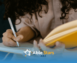 A BCBA student writing in a yellow notebook with a white pen while sitting on a couch, studying for BCBA exam.