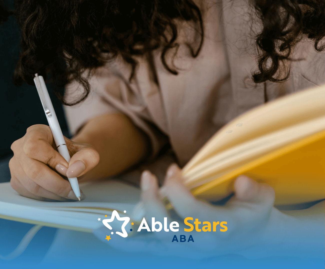 A BCBA student writing in a yellow notebook with a white pen while sitting on a couch, studying for BCBA exam.