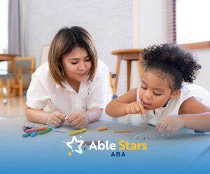 BCBA and young girl lying on the floor drawing with crayons on large paper in ABA therapy.