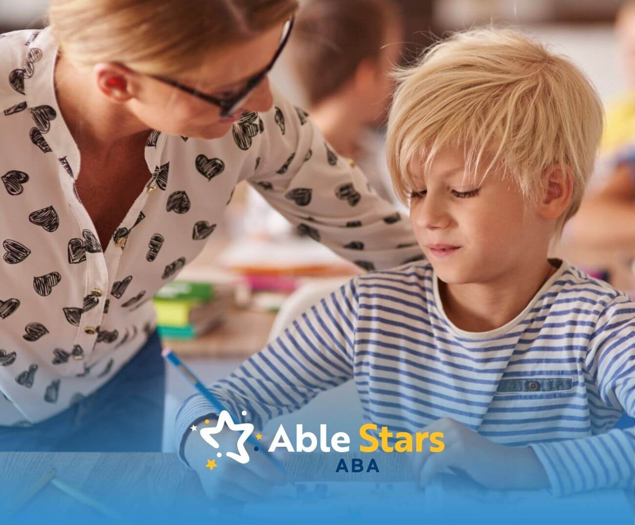 ABA therapist assisting a young boy with his writing during school-based ABA therapy.