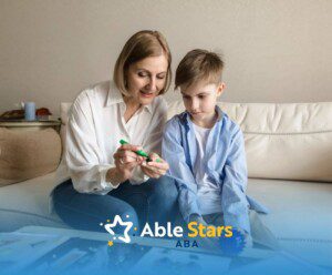 ABA therapist helping a young boy with an art project on a couch.