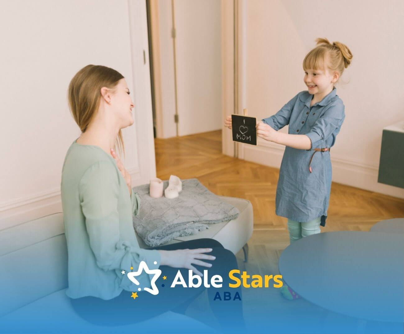 Girl presenting "I love MOM" sign to mother, asking her to stay during ABA therapy.