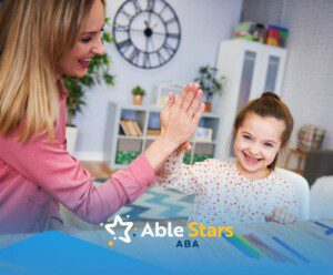 ABA therapist and girl smiling and giving a high-five during learning activity in ABA therapy.