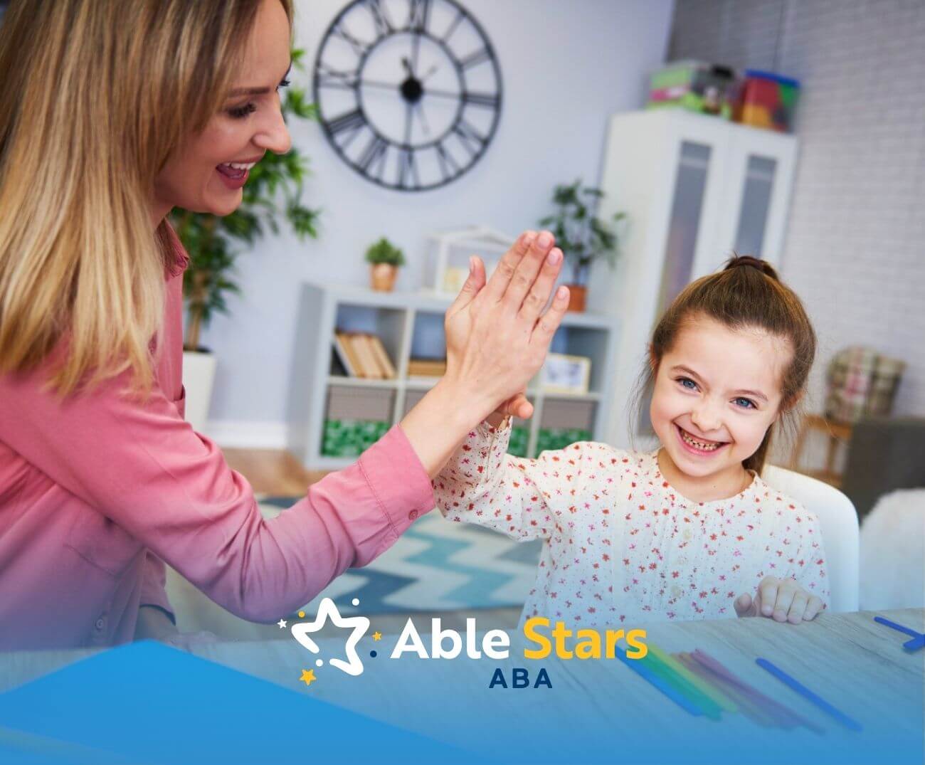 ABA therapist and girl smiling and giving a high-five during learning activity in ABA therapy.