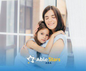 Mother and daughter hugging by a window, both wearing light blue clothes after ABA therapy.