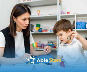 ABA therapist and boy interacting with small bells and wooden toys in ABA therapy.