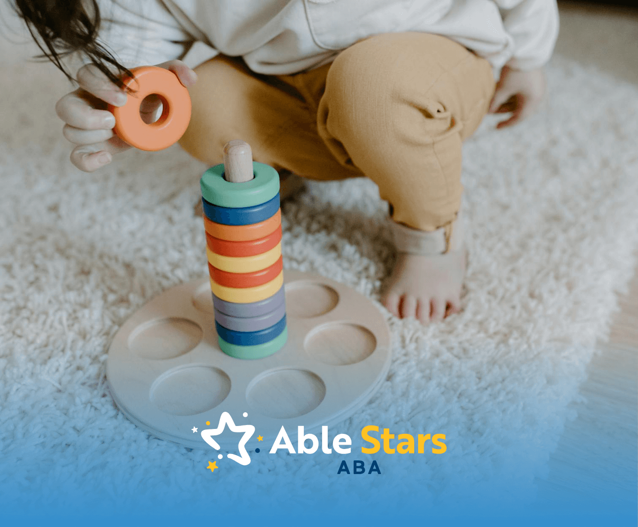 An autistic child stacking colorful wooden rings on a toy tower on the floor during ABA therapy session in MD.