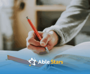 RBT student's hand holding a pen over an open notebook with a cup nearby, preparing to write and study for the RBT exam.