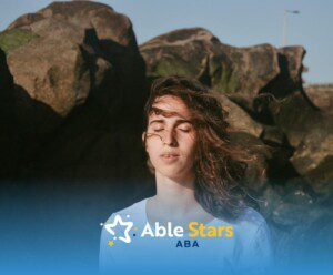 An autistic woman outdoors with eyes closed, relaxing in the wind.