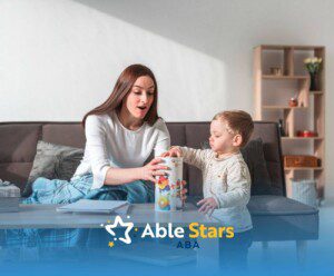 ABA therapist playing with a young boy and a toy container on the couch in ABA therapy.
