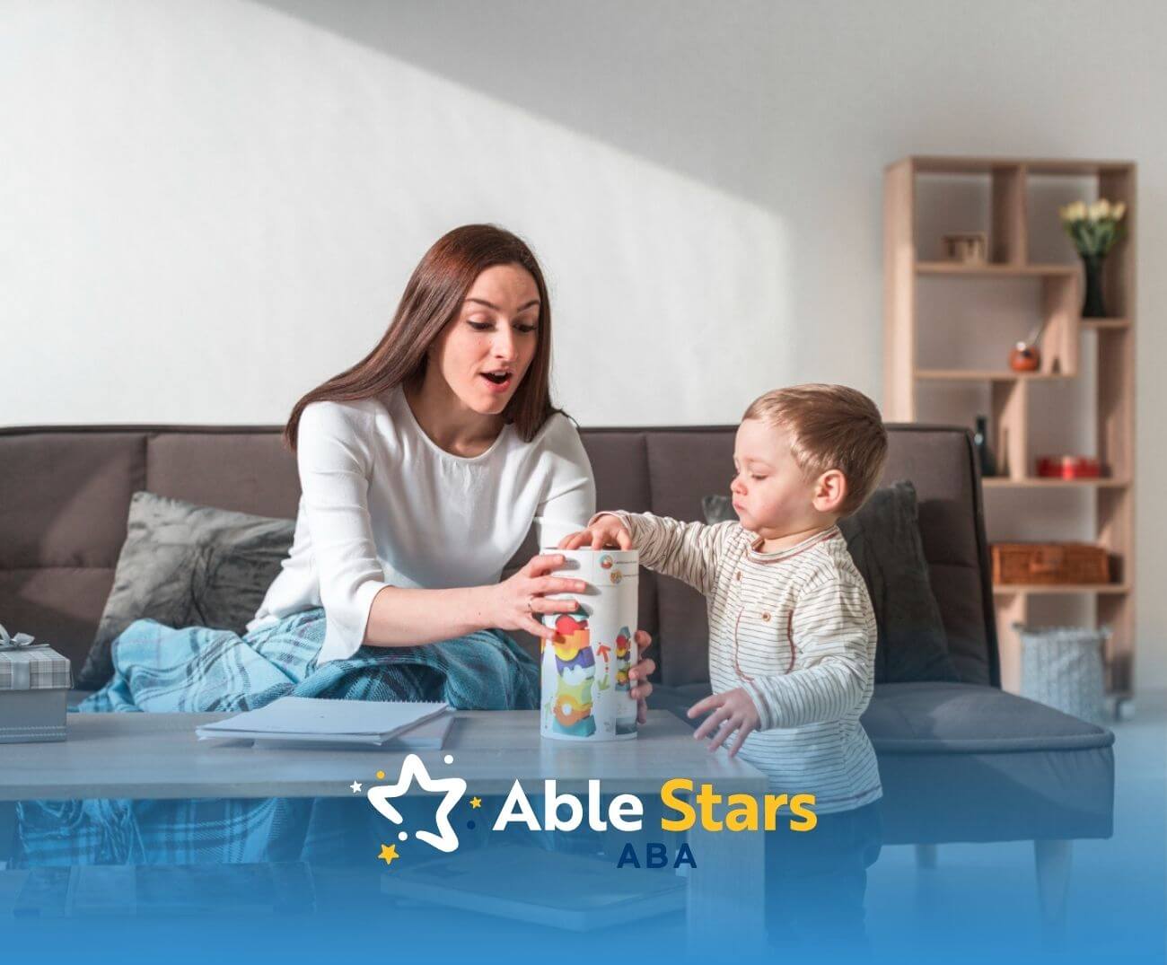 ABA therapist playing with a young boy and a toy container on the couch in ABA therapy.