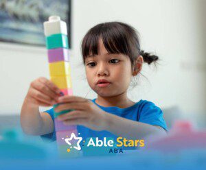 Young gir with autism stacking colorful toy blocks attentively in ABA therapy.