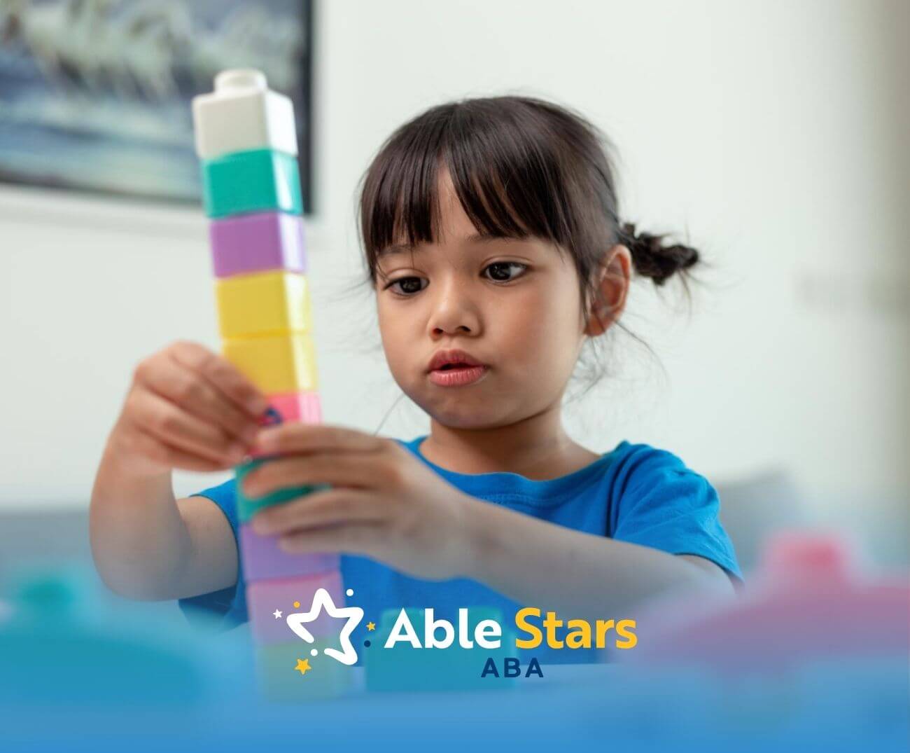 Young gir with autism stacking colorful toy blocks attentively in ABA therapy.