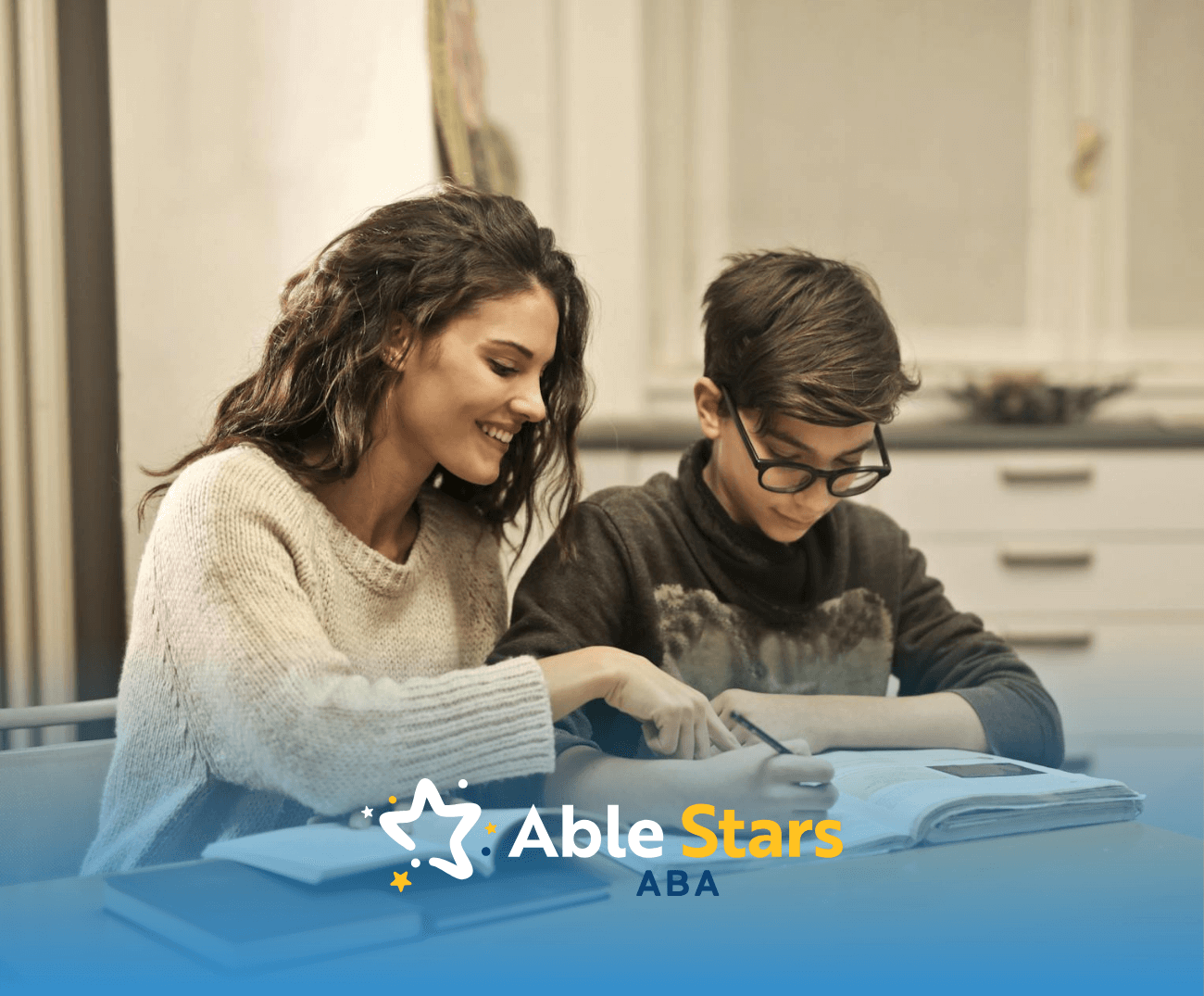 Smiling RBT tutoring an autisticteen boy with open books during an in-home ABA therapy session in Maryland.