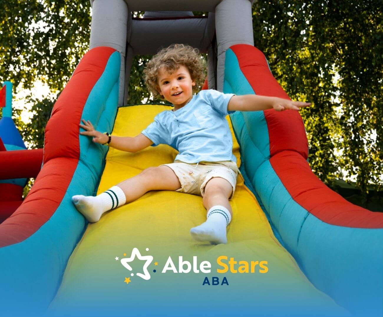 A boy with autism sliding down a colorful inflatable slide.