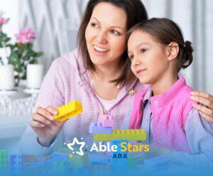 ABA therapist smiling while playing with colorful toy blocks with an autistic girl in ABA therapy.