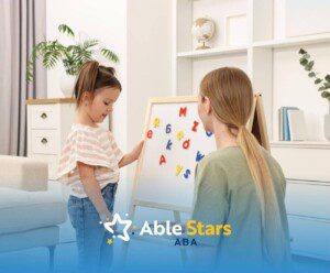 Young girl with autism placing magnetic letters on a board with an ABA therapist sitting nearby.