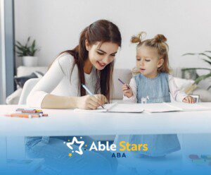 BCBA and toddler with autism drawing together at a white table at home.