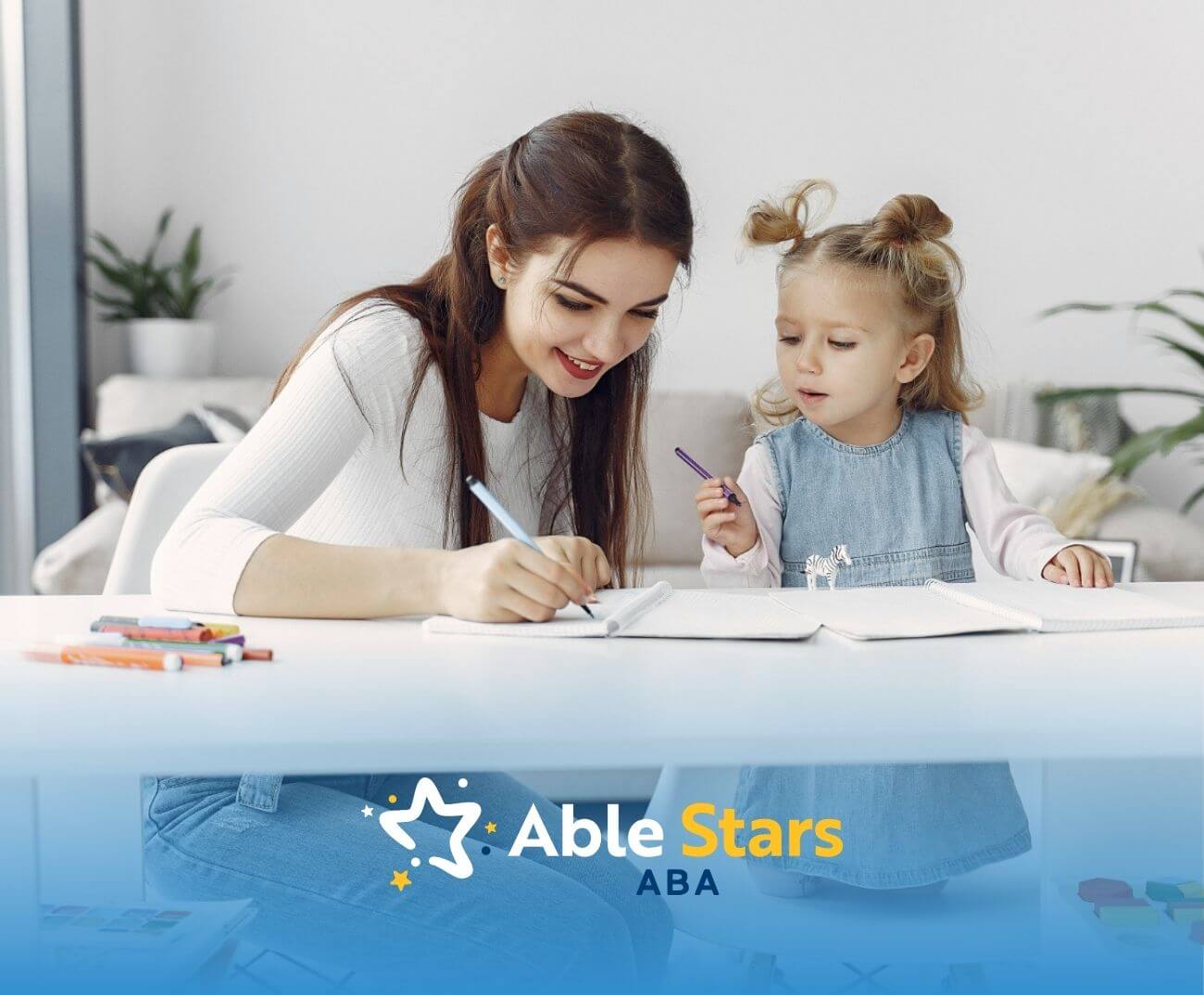 BCBA and toddler with autism drawing together at a white table at home.