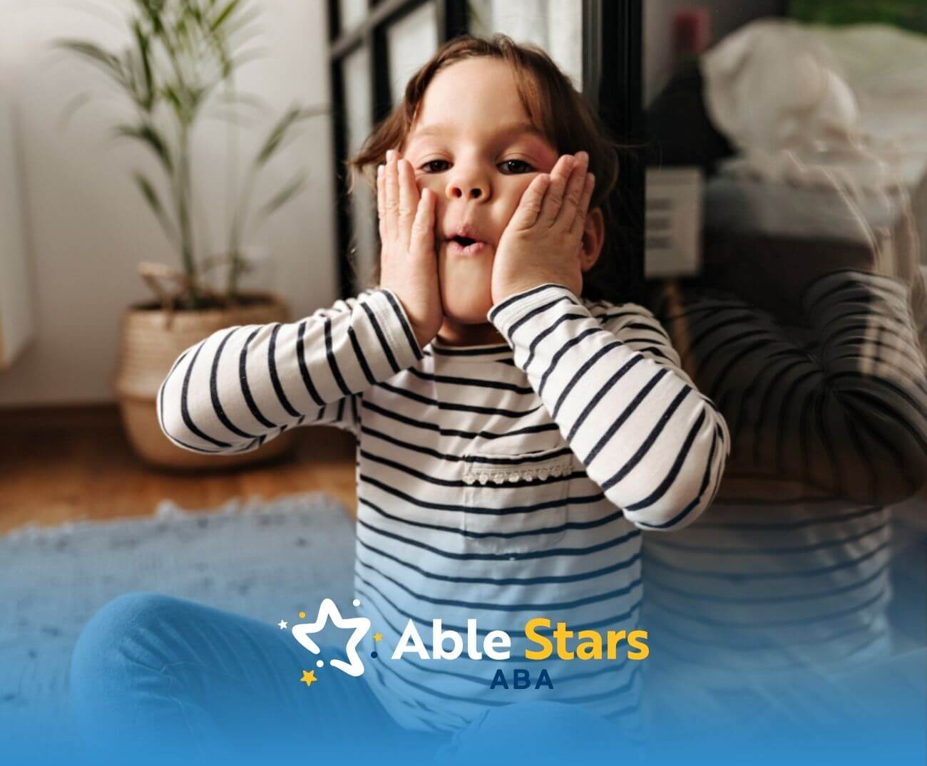 Child with autism holds cheeks making funny face in ABA therapy.