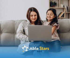 BCBA and girl with autism sitting on a couch using a laptop together.