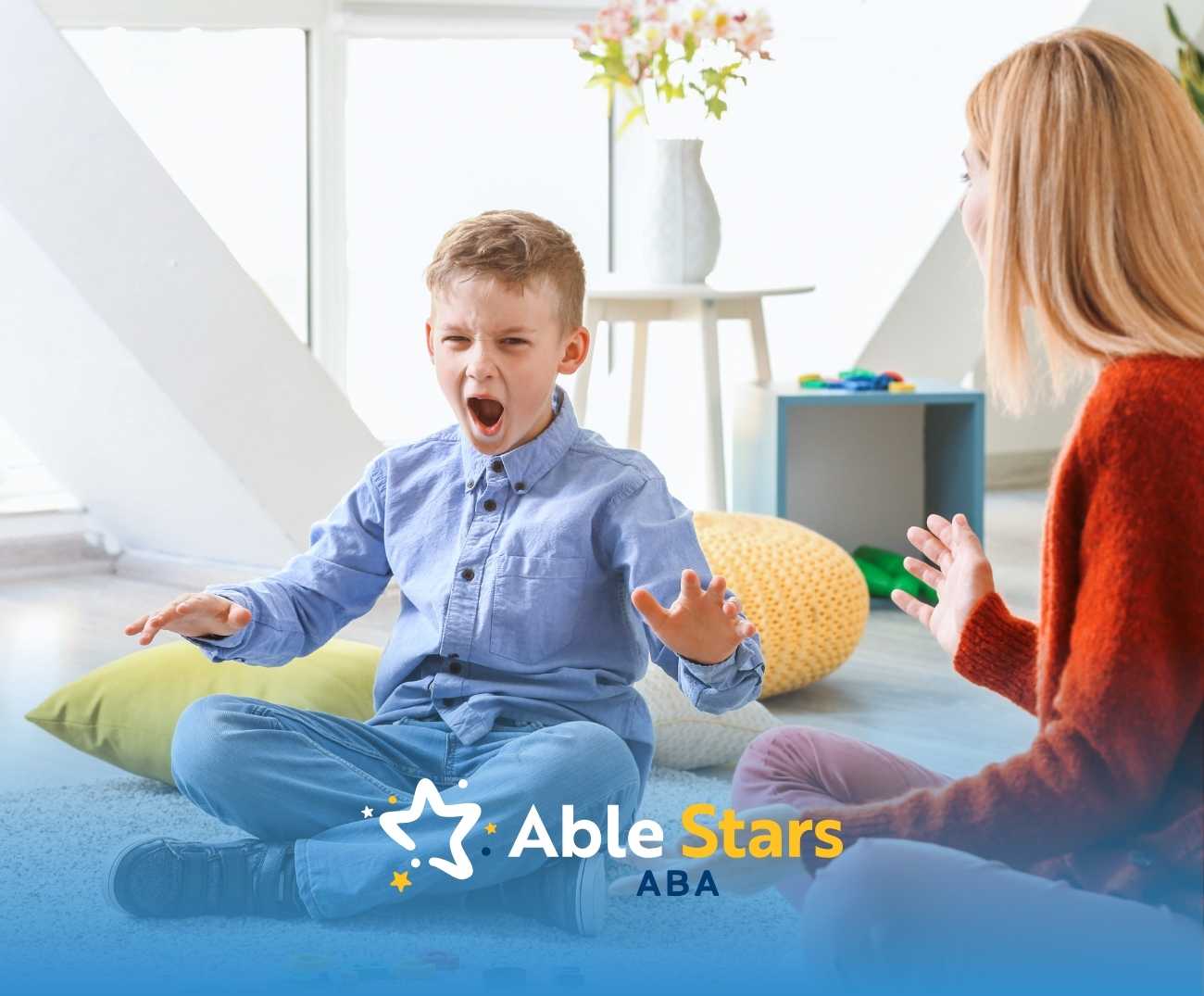 A young boy in a blue shirt appears excited, sitting cross-legged on the floor, gesturing with his hands. A woman listens attentively. The atmosphere is bright and engaging, with colorful cushions and toys around.
