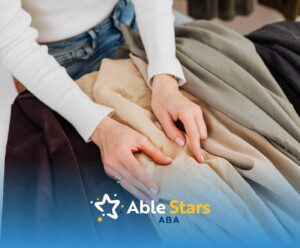 A person in a white sweater and jeans is touching various colored fabric swatches on a table.