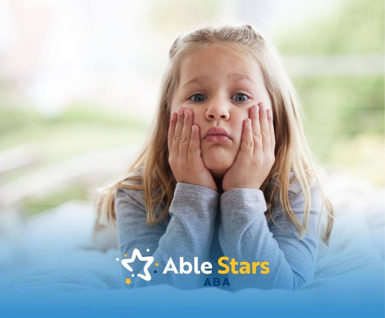 Young girl with autism resting her chin on her hands with a sad or bored expression.