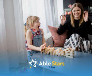 Little girl with autism excited as a tower of wooden blocks tumbles near her.