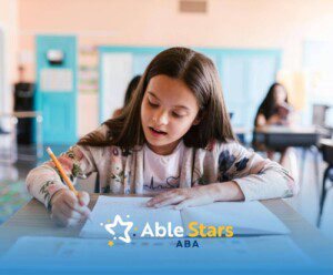 A young girl sits in a classroom, deeply focused on her writing task, showing concentration and quiet determination.