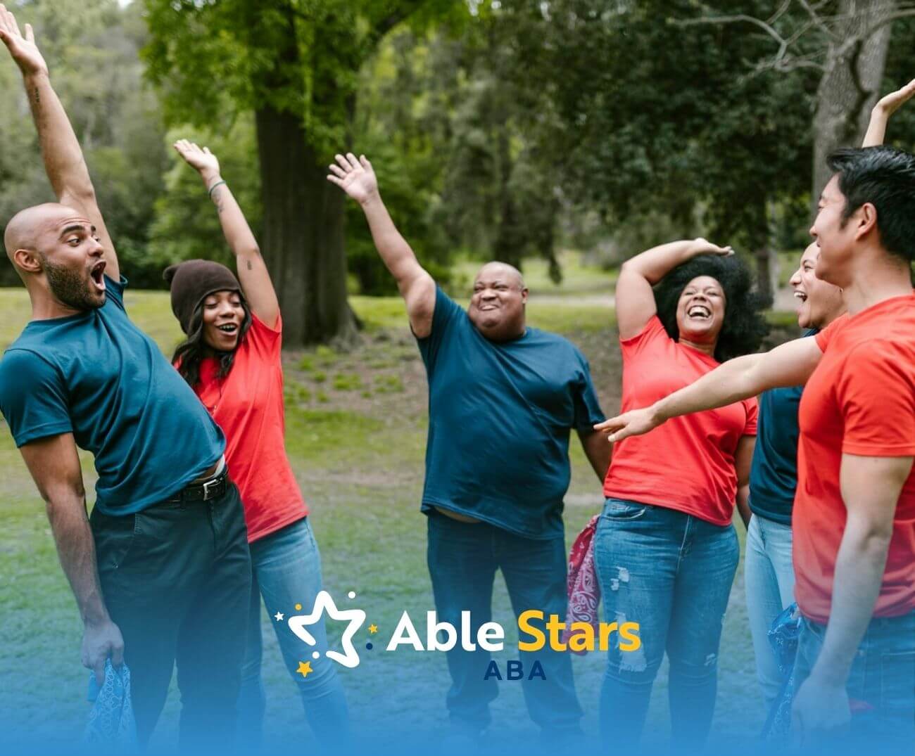 Grown-ups in red and blue shirts laugh and motion animatedly while playing a lively team game outside.