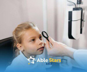 A young girl sits patiently during an eye exam at the doctor’s office, focusing as the physician checks her vision.